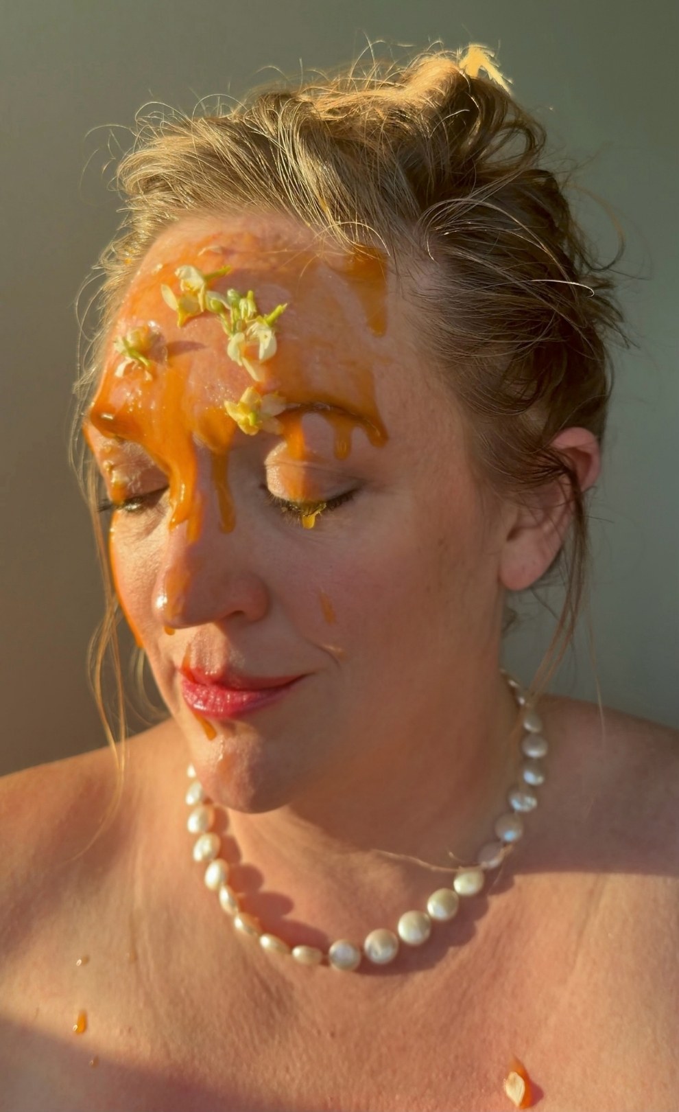 Taste and See, 2 of 5. Head bowed, eyes closed, honey running from the forehead over the eyes, nose and lips; white flowers in the honey, a pearl necklace.