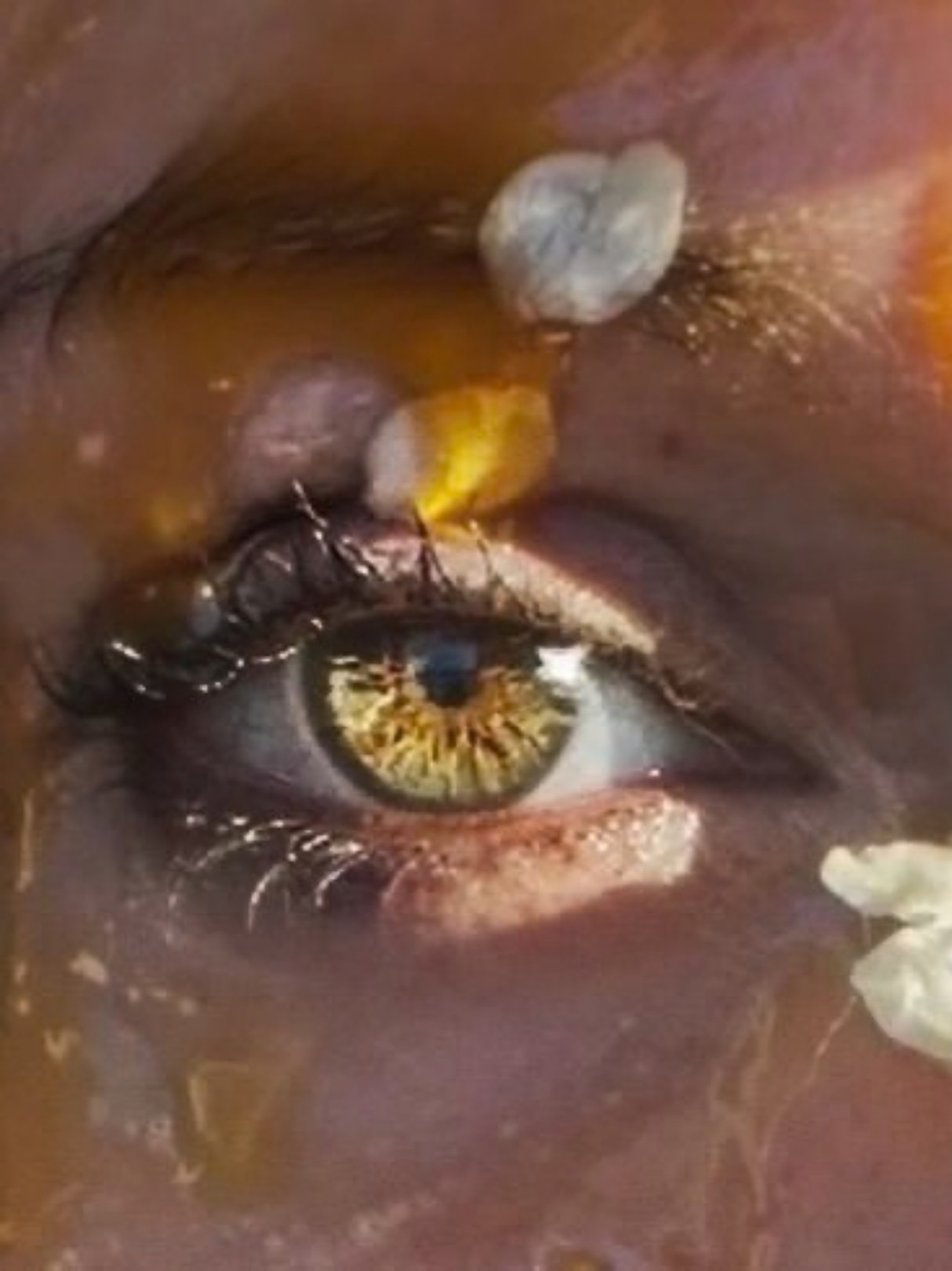 Taste and See, 5 of 5. Close crop of an open eye with a gold iris, honey and petals around it.